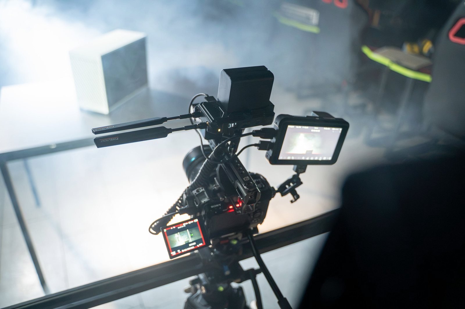 A camera rig with two monitors set up over a glass table in thick haze.