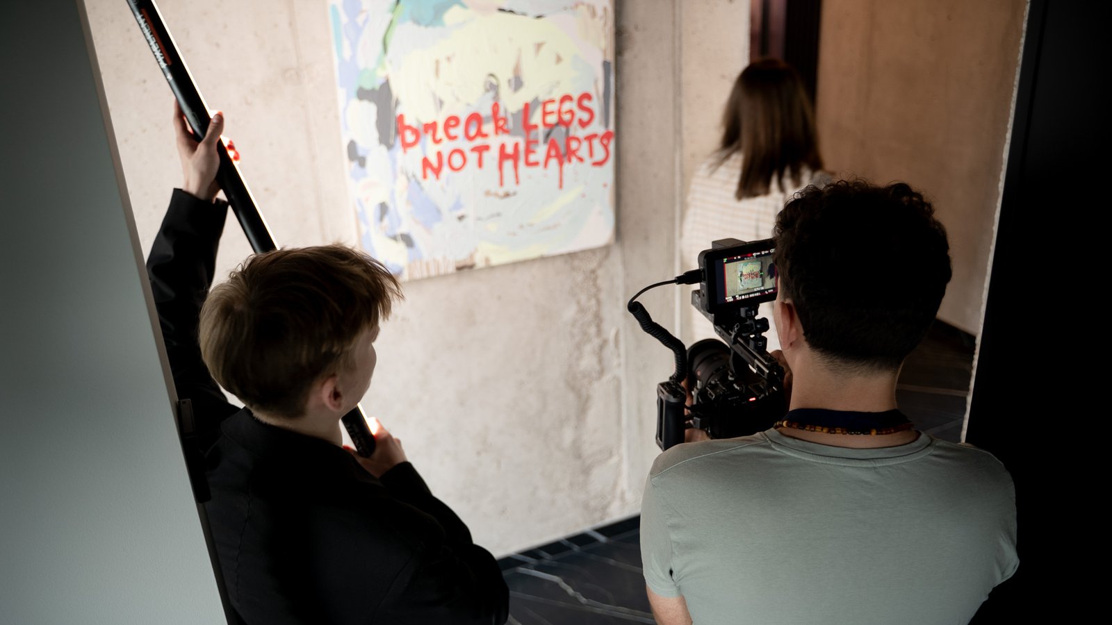 Two-person Story Craft crew filming a subject with an LED light in front of a graffiti mural
